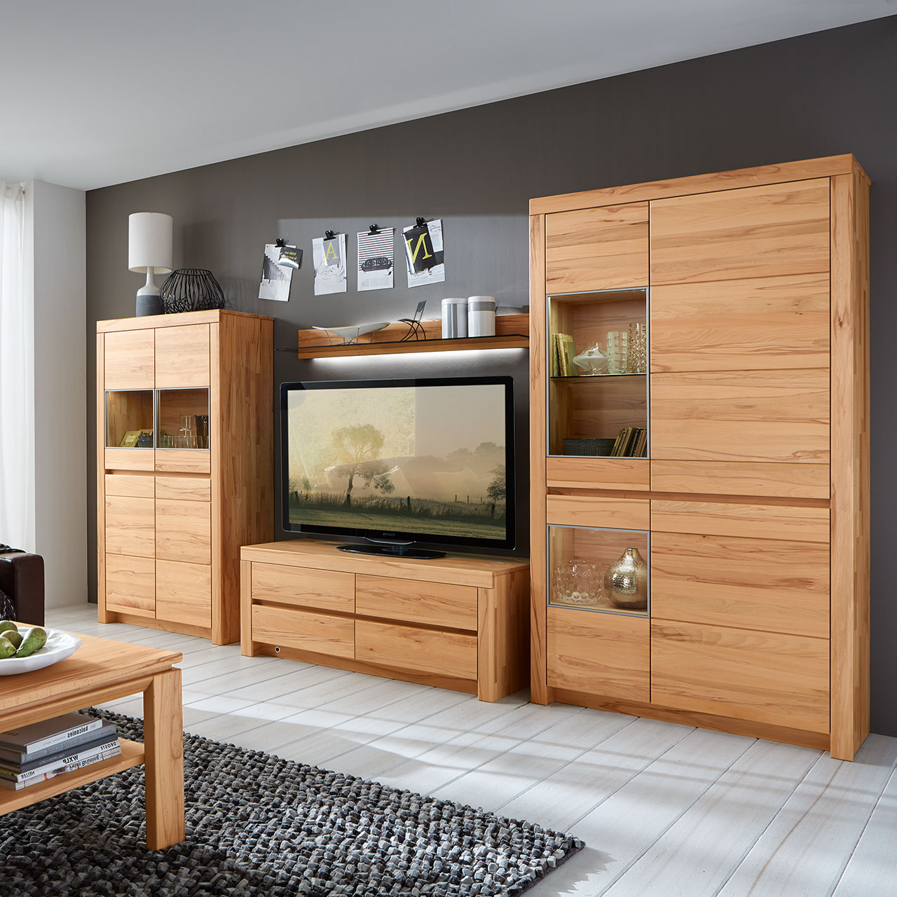Wohnwand in massiver Kernbuche Type 3106 mit ein Lowboard, ein Zeilenschrank und einem Highboard bestehend aus 4 Türen mit zwei Vitrinenfächern nebeneinander angeordnet, als Ambiente Bild.