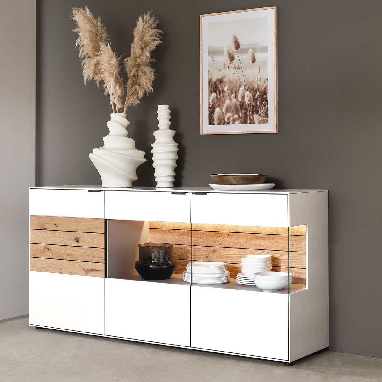 WM 2380 Sideboard 2844 Lack weiss Modernes Sideboard aus Lack weiß, mit einem großen und besonderen Vitrinenfach das Seitlich einzusehen ist, die Rückwand in Balkeneiche bietet einen schönen Kontrast zur glatten Front.