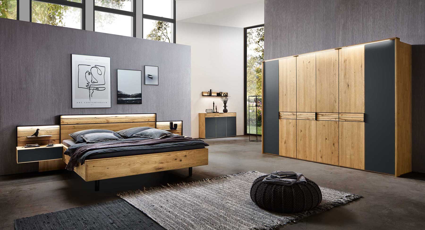 Schlafzimmer WSM 4300 Banner zeigt Schlafzimmer mit Doppelbett, zwei Konsolen in Wildeiche und 6-türigen Kleiderschrank mit seitlich senkrecht angeordneten Mattglas carbonfarbig Akzent, mittige Banderole in Balkeneiche.