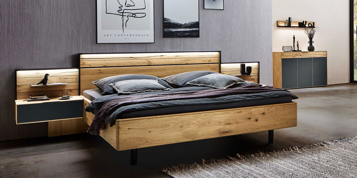 Wöstmann Betten Schlafkomfort mit den Betten von Wöstmann, gefertigt aus edlen Hölzern und erstklassigen Materialien, gezeigt wird ein Doppel Bett in Wildeiche mit Konsolen und Pandeelaufsätze inkl. Beleuchtung.