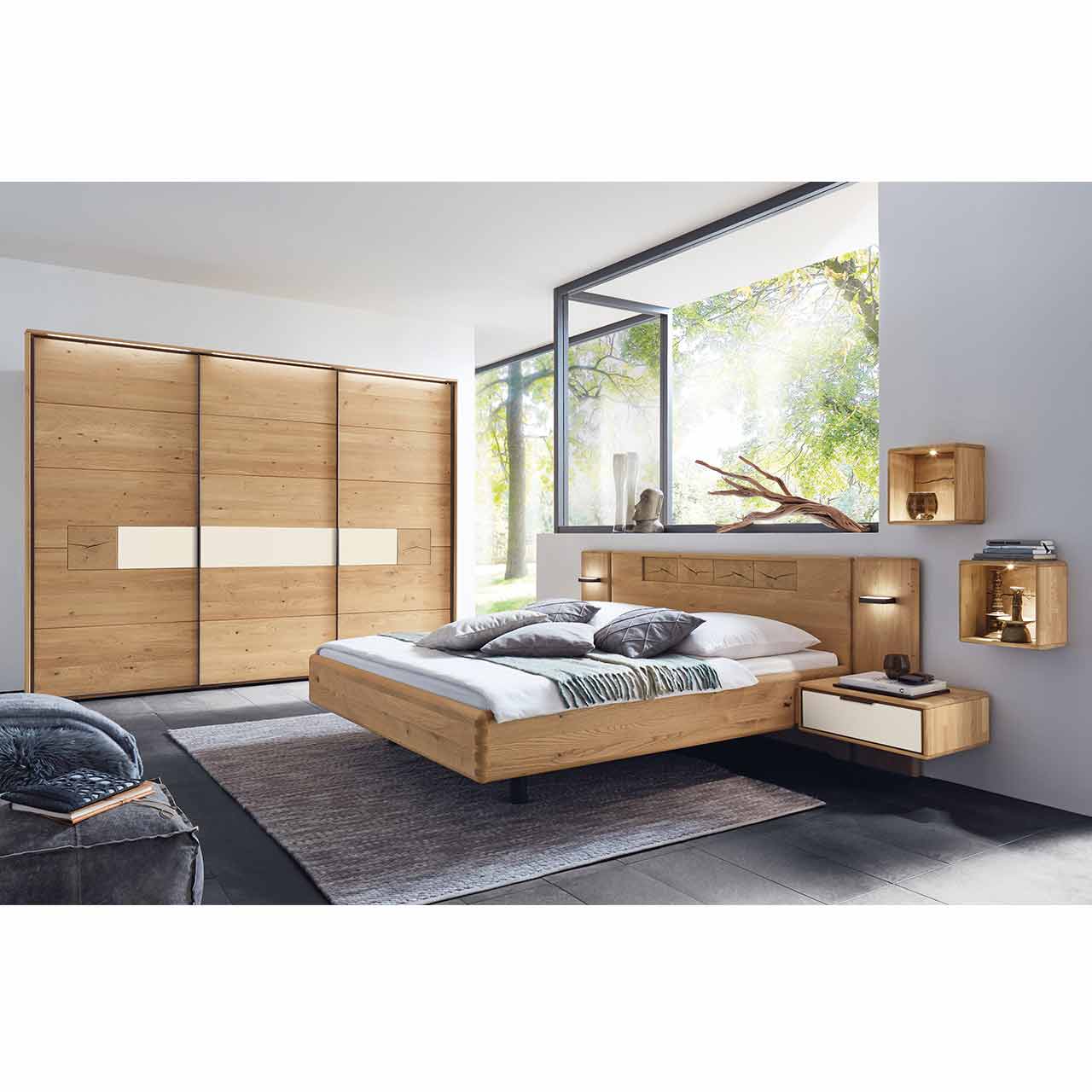WSM 1600 Schiebetürenschrank, Ambiente Bild Schlafzimmer mit Doppelbett Konsolen paassende Paneelaufsätze und Schiebetürenschrank, mit Passepartout und Beleuchtung, gezeigt mit Hirnholz und Lack Magnolie Akzent.