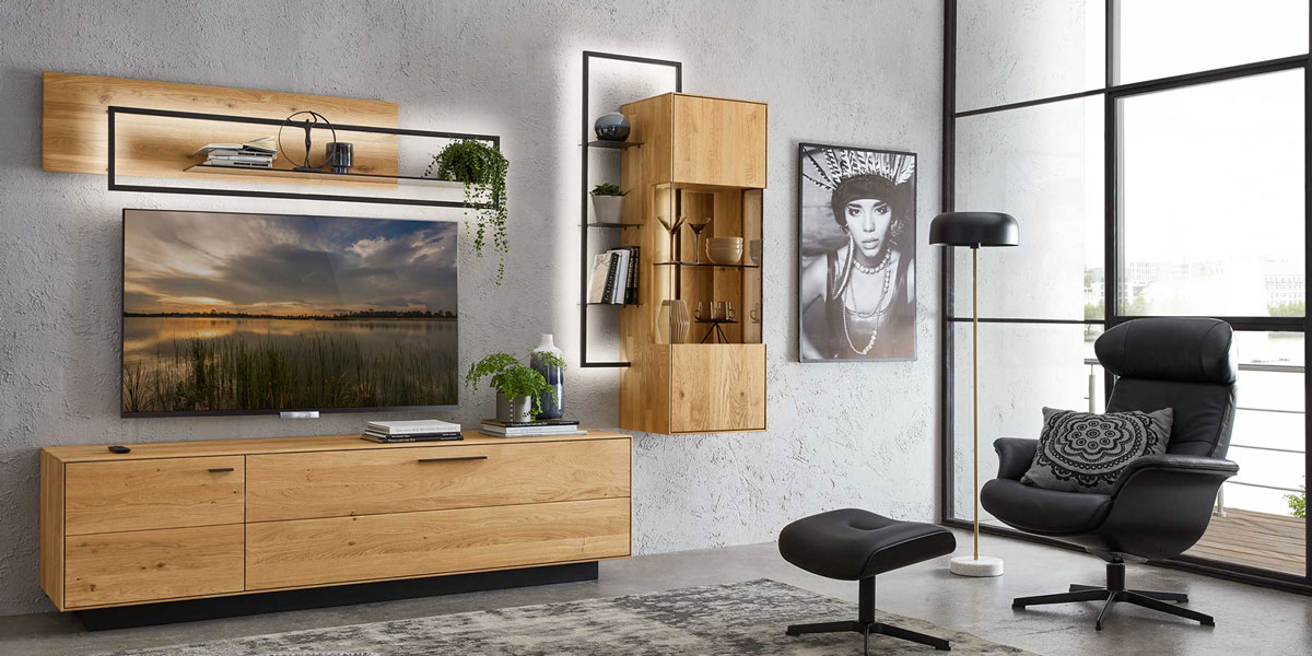 Wöestmann Hängeelemente Entdecken Sie die vielseitigen Hängeelemente von Wöstmann: Banner zeigt eine 3-teilige Wohnwand mit einem Lowaboard, Hängevitrine mit seitlich angesetzten beleuchteten Metallregal, passend dazu ein Wandboard aus der gleichen Serie.